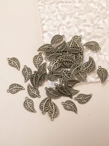 Flat lay of antique bronze hollow leaf charms with intricate filigree for DIY jewelry making