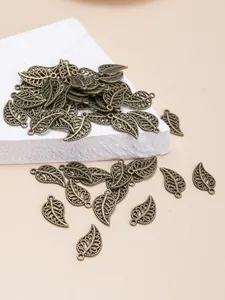 Macro shot of bronze hollow leaf pendants for DIY jewelry making on stone platform