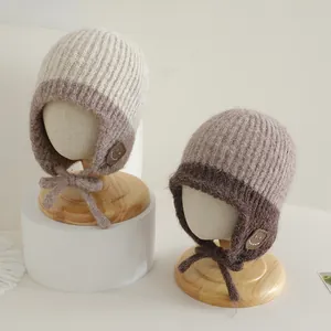Close-up van de gebreide babymuts met oorkleppen en decoratieve smiley-patch