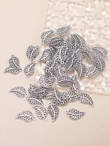 Macro shot of antique silver hollow leaf charms for DIY jewelry making on glass