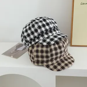 Close-up of thick plaid wool newsboy caps for kids in black and brown checkered patterns