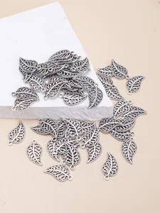 Close-up of silver leaf alloy charms with filigree hollow design and hanging loop