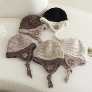 Gebreide kindermuts met oorkleppen, schattige smile-patch en pompon in vijf kleuren