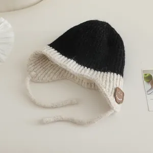 Detail van de tweekleurige gebreide baby muts met oorkleppen en vrolijke smile patch