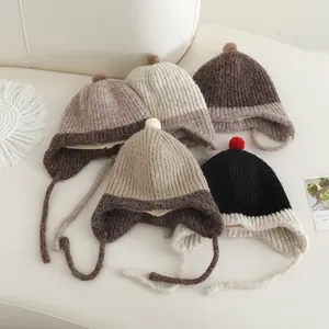 Gebreide baby wintermutsen met oorkleppen en pompons in warme aardetinten