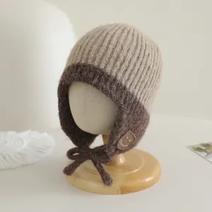 Detail van gebreide babymuts met tweekleurige vezels en een vrolijk smiley-embleem