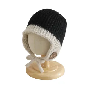 Gebreide wintermuts voor baby's met oorkleppen, pompons en schattige smiley in zwart-beige