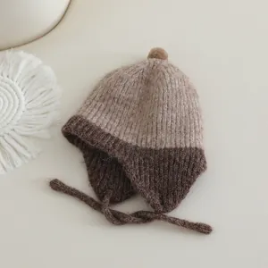 Bruine gebreide babymuts met oorkleppen en pompon op een warme en comfortabele achtergrond
