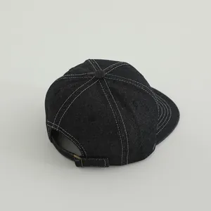 Detail einer schwarzen Denim-Baseballkappe mit weißen Kontrastnähten und Metallschnalle