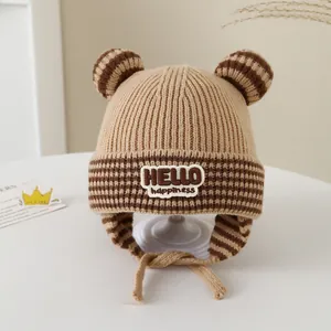 Close-up of winter baby knitted hat with bear ears, brown stripes and HELLO happiness patch