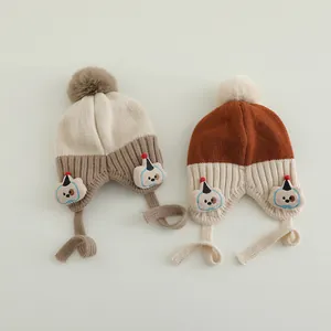 Detailansicht der Baby-Strickmützen mit Bommel, Ohrenklappen und Hundeflicken