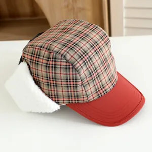 Detail of red and brown plaid winter trapper hat with white faux fur earflaps