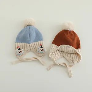 Detail von gestrickten Baby-Ohrenklappenmützen mit Bommeln und süßer Tierstickerei