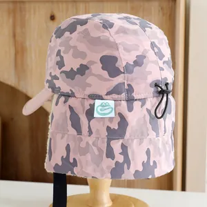 Detail of kids winter camouflage hat featuring plush earflaps and adjustable drawstring