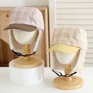 Detail of winter trapper hats featuring plaid patterns and soft fleece lining on wood stands