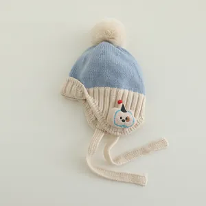 Detail einer Baby-Strickmütze mit hellblauem Patchwork, Pompon und Hunde-Stickerei