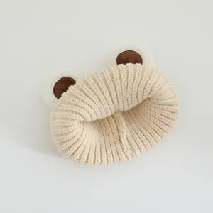 Close-up of beige knitted baby hat featuring cute fuzzy bear ears and soft ribbed texture