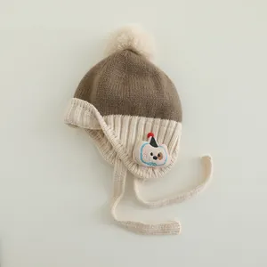 Detail einer Baby-Strickmütze mit Pelzbommel und aufgesticktem Cartoon-Hunde-Patch