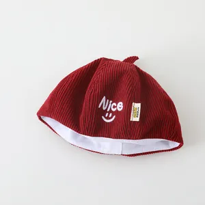 Nahaufnahme der Cordstruktur und Nice-Stickerei auf der weinroten Kinder-Beanie