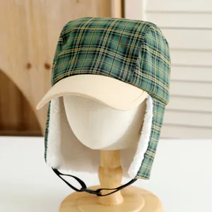 Detail of winter trapper hat showing green plaid fabric and warm white faux shearling lining