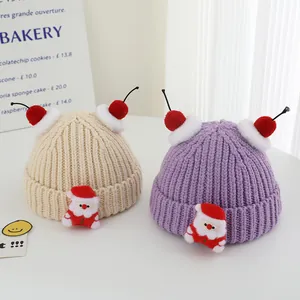 Close-up of knit winter hats with festive Santa patches and red cherry pom-poms