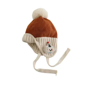 Winter-Strickmütze für Babys mit Ohrenklappen, Bommel und Hundemotiv in Gelb-Beige
