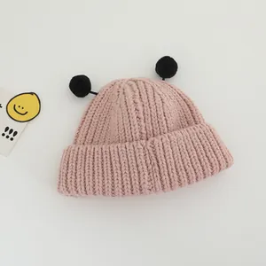 Détail du bonnet en tricot rose pour enfants avec pompons noirs et texture en laine