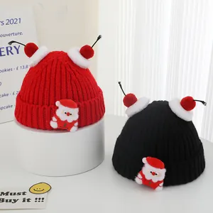 Close-up of red and black Christmas knit hats featuring cute Santa Claus patches