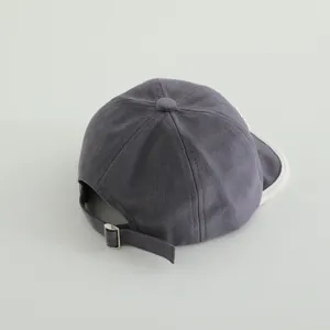 Detail view of the metal buckle and adjustable strap on a dark gray cotton baby cap