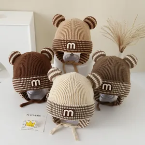 Detailed view of four brown knit baby hats with earflaps and cute striped bear ears