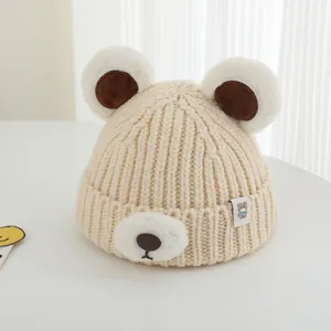 Detail of beige knit winter hat for kids featuring cute bear ears and plush animal face