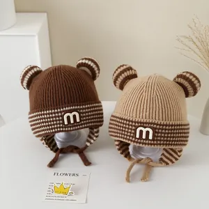 Detail of baby winter knit hats with bear ears, M-patch, and warm earflaps in brown and beige