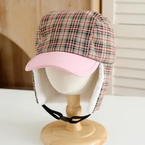 Detail view of winter plaid hat with orange-black pattern and soft white faux fur lining
