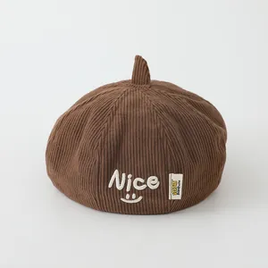 Detailtextur der braunen Cord-Kindermütze mit besticktem Nice-Smiley-Gesicht