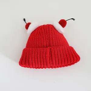 Detailed close-up of red knit winter hat featuring decorative cherry-shaped faux fur pom-poms