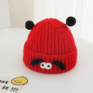 Détail du bonnet rouge en maille côtelée avec de grands yeux et pompons noirs doux