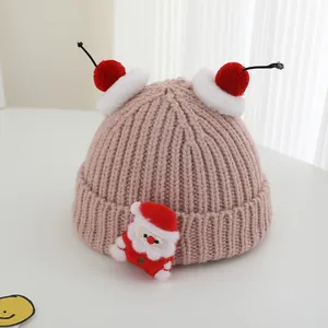 Close-up of pink knitted winter hat with Santa patch and red-white pom-poms for kids