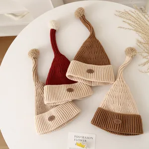 Chic knit Christmas elf hats with fluffy pom-poms and leather labels in neutral tones