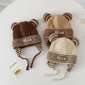 Three knitted baby hats in brown, tan and cream with bear ears and chin straps