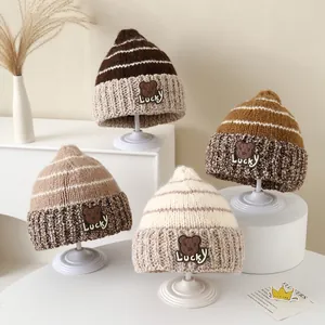 Dettaglio di berretti invernali in maglia a righe per bambini con toppa a orsetto