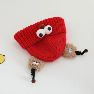 Winter red knitted baby hat with large 3D eyes and cute plush charms for children