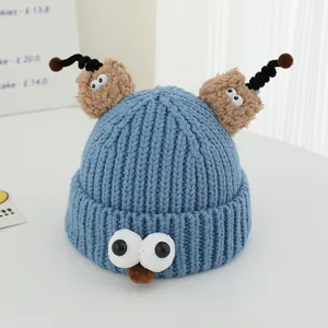 Close-up of blue monster knit hat featuring 3D eyes, fuzzy ears, and spiral tentacles