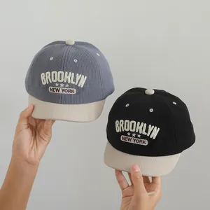 Detail of Brooklyn embroidery on corduroy kids baseball caps in blue and black colors