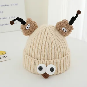 Close-up of beige knit monster hat with large 3D eyes and brown fuzzy ears detail