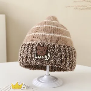 Dettaglio del cappello invernale in maglia bicolore con toppa a forma di orso Lucky