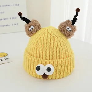 Detail of yellow knit monster hat with large eyes and brown plush antennae for kids