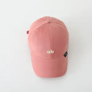 Detail van roze katoenen baseballpet met wit AB-borduursel en een klein geweven label