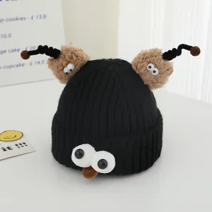Detail of funny knitted baby hat with big white eyes and brown plush antennae
