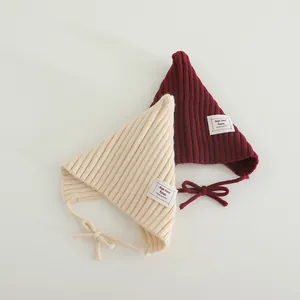 Detailed knit texture of cream and burgundy infant pixie hats with chin straps