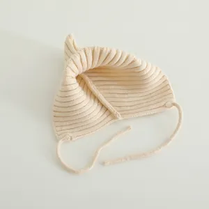 Close-up of knit texture and bunny ears on cream baby winter hat with chin straps